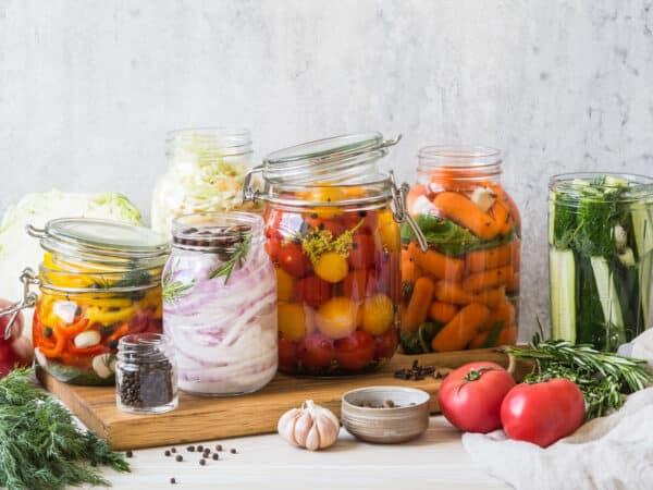 Cooking pickled vegetables. Salting various vegetables in glass jars for long-term storage. Preserves vegetables in glass jars. Variety fermented green vegetables on a wood board